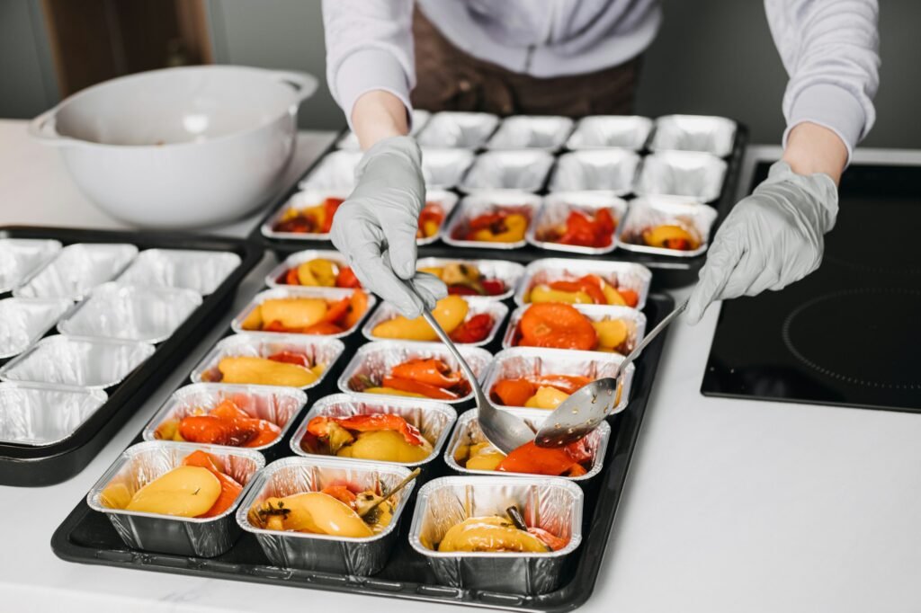 Caterer in a professional kitchen preparing individual servings of roasted vegetables, showcasing